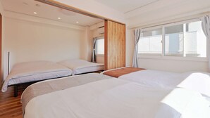 A hotel room with two beds, a wooden wardrobe, a window with curtains, and a ceiling with recessed lighting. - V.Close to Shinjuku Kabukicho H (Shinjuku-ku)