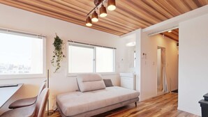 A modern bedroom with a sofa bed, wooden flooring, and a ceiling with exposed beams. - V.Close to Shinjuku Kabukicho H (Shinjuku-ku)