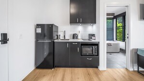 A modern kitchen with black cabinets, a built-in microwave, and a refrigerator.