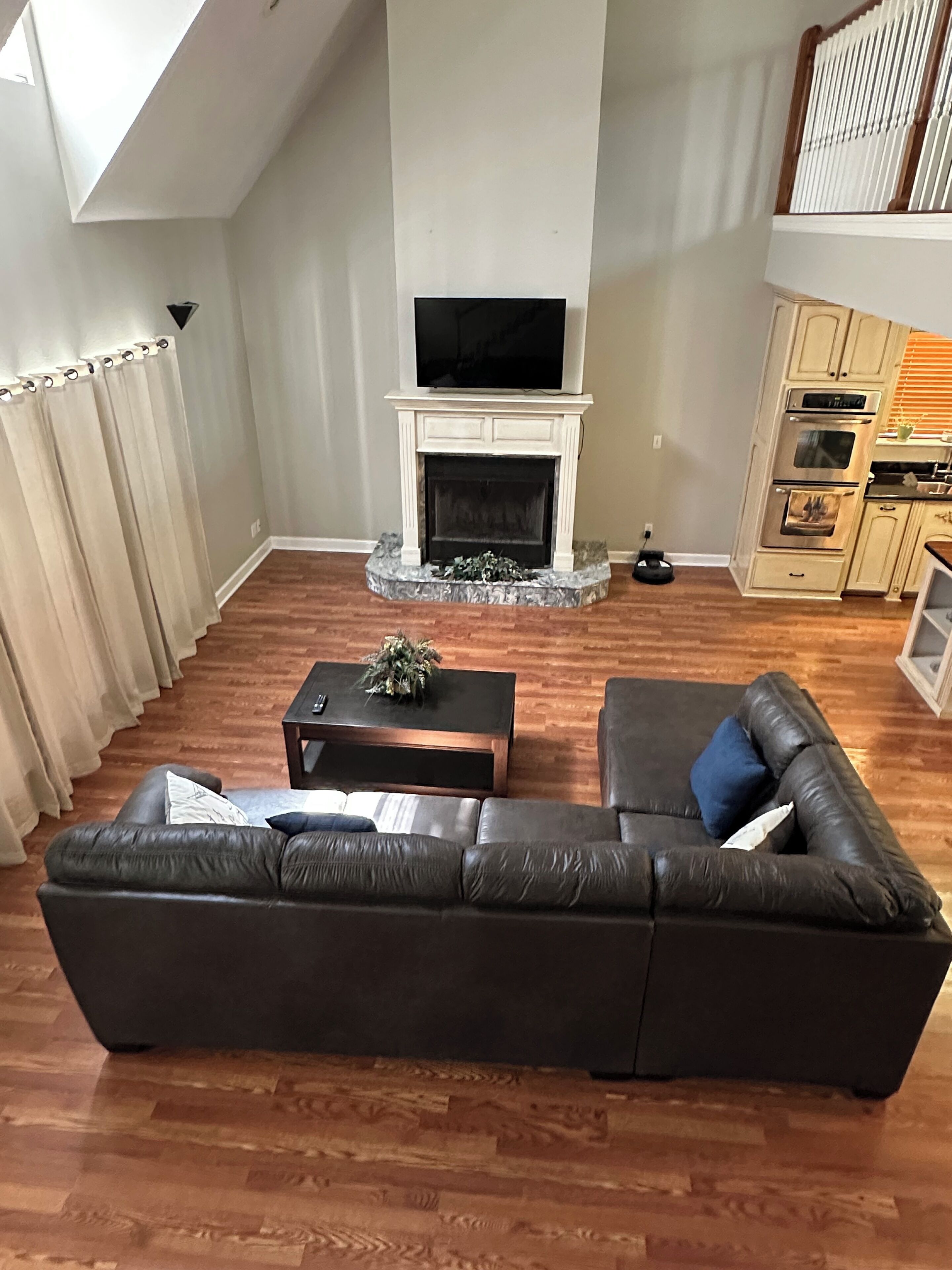 Een woonkamer met een open haard, een televisie, een bank en een keukenhoek.