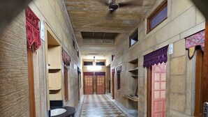 A corridor with checkered flooring, wooden doors, and a ceiling fan. - Hotel Blue Diamond Jaisalmer (Jaisalmer)