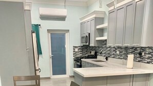 A modern kitchen with a central island, white cabinets, and a tiled backsplash. - Charming 2-bedroom apartment with AC, WiFi in wonderful Nassau (Nassau)
