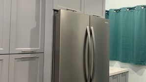 A kitchen with grey cabinets, a stainless steel refrigerator, and a teal shower curtain. - Charming 2-bedroom apartment with AC, WiFi in wonderful Nassau (Nassau)