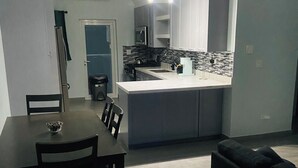 A modern kitchen with a central island, a dining area with a table and chairs, and a dark-colored sofa. - Charming 2-bedroom apartment with AC, WiFi in wonderful Nassau (Nassau)