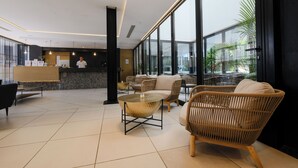 Eine moderne Lobby mit einer Rezeption, einer Sitzecke und großen Fenstern mit Blick ins Freie.