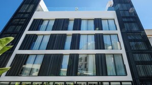 Ein modernes Gebäude mit weißer Fassade, großen Fenstern und schwarzen, vertikalen Lamellen.