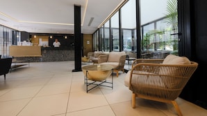 Un vestíbulo moderno con un mostrador de recepción, una zona de estar y grandes ventanales que ofrecen vistas al exterior.