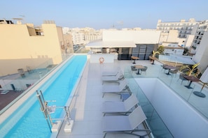 Uma área de piscina no terraço com espreguiçadeiras e um bar.
