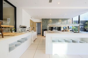 Un área de cocina moderna y bien iluminada con una disposición tipo buffet, incluyendo una vitrina de vidrio y una encimera de madera.