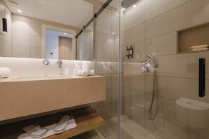 A modern bathroom with a glass-enclosed shower, a vanity with a mirror, and neatly arranged towels. - Azuline Hotel M (Sant Antoni de Portmany)