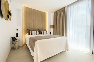Habitación de hotel moderna con una cama grande, teléfono en la mesita de noche, lámpara y vistas al exterior.