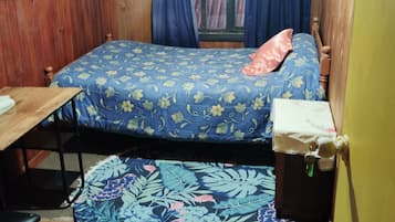 Um quarto pequeno, decorado com mobiliário de madeira, com uma cama, uma mesa e uma cadeira.