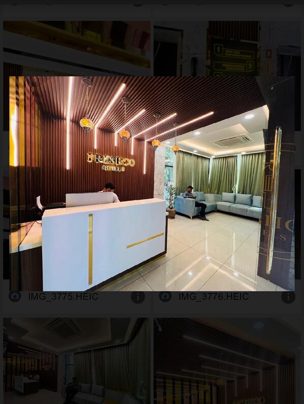 Ein Hotel-Empfangsbereich mit modernem Design, der einen Empfangstresen, eine Sitzecke und ein sichtbares Hotelschild umfasst.