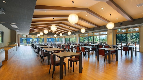 A spacious dining area with long tables and chairs, large windows, and hanging spherical light fixtures. - Aso Hakuunsansou (Aso)
