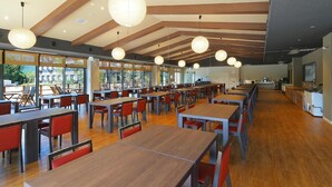 A spacious dining area with multiple tables and chairs, large windows providing natural light, and a modern ceiling design. - Aso Hakuunsansou (Aso)