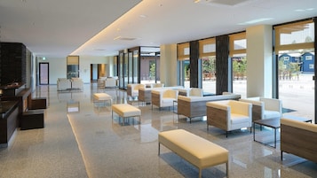 A spacious lobby with a long bench seating area, a reception desk, and large windows offering a view of the outside.
