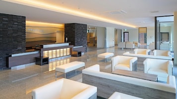 A modern lobby with a reception desk, seating area, and a stone wall.