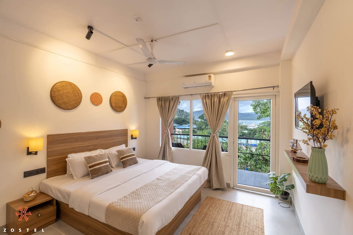 Une chambre moderne avec un grand lit, un ventilateur de plafond et une vue sur l’extérieur grâce à une porte coulissante.