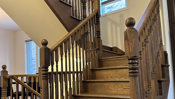 A wooden staircase with a handrail and balusters, leading to an upper floor. - Newly Built Detached Home! Close to nature and city.  (Brampton)