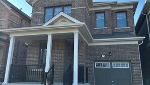 A two-story house with a front porch, a garage, and a brick facade. - Newly Built Detached Home! Close to nature and city.  (Brampton)