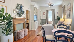 A spacious living room with a fireplace, wooden flooring, and a ceiling fan.