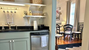 A kitchen with a checkered floor, a built-in oven, and a sink. There are baskets on the shelves and a towel hanging on the oven handle.