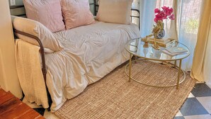 A bedroom with a bed, a small round table with a vase, and a checkered floor.