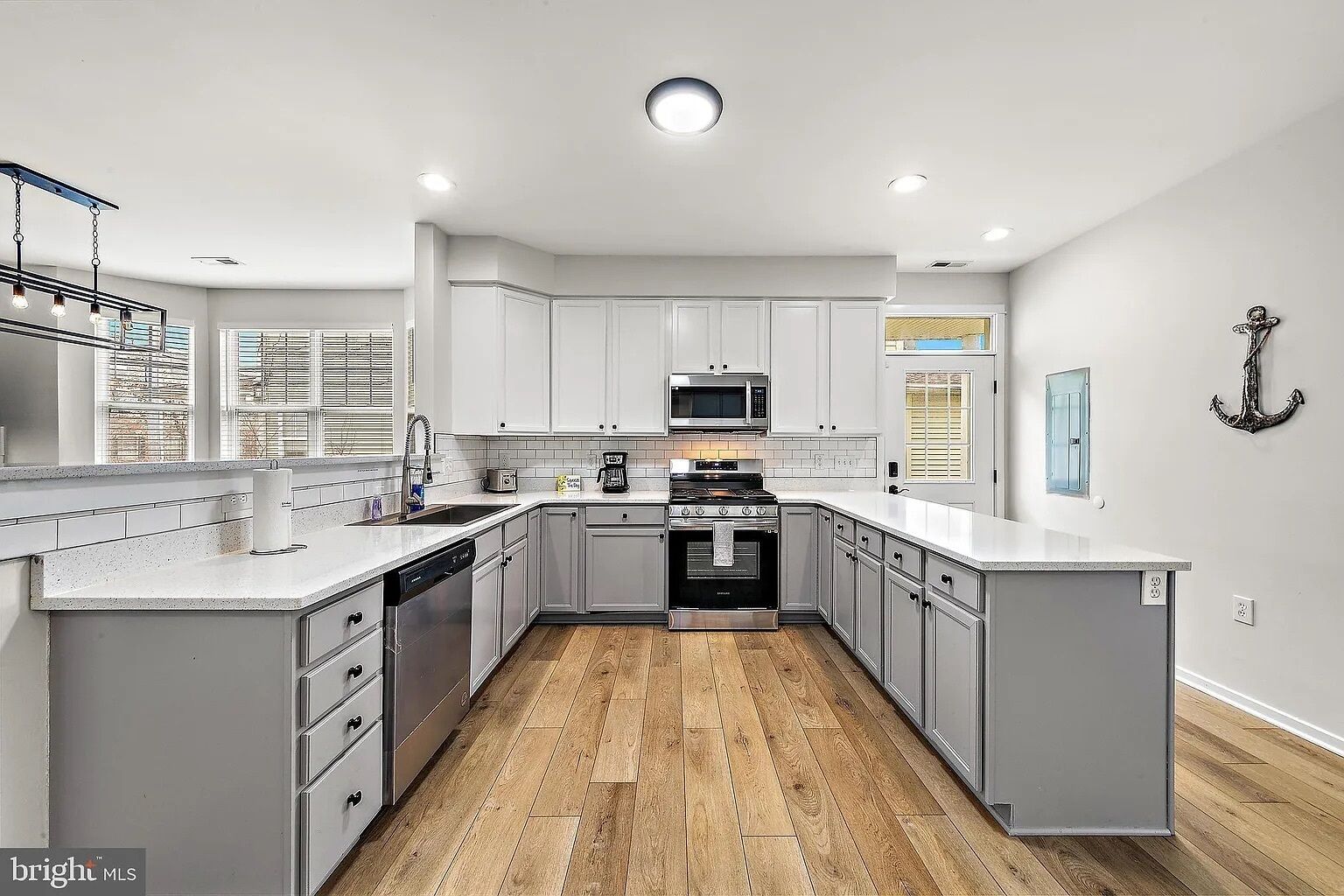 A modern kitchen with grey cabinets, a dishwasher, a stove, and a microwave.