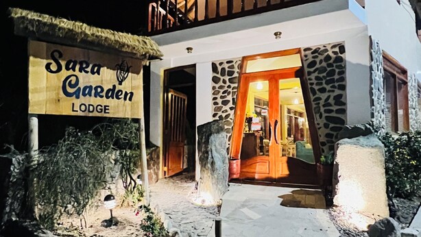 A two-story building with a sign reading "Sara Garden Lodge." - Lodging in Ollantaytambo living inka city with viewpoint to mountains (Ollantaytambo)
