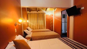 A hotel room with a large bed, two bedside tables, a flat-screen TV mounted on the wall, and a curtain. - Lodging in Ollantaytambo living inka city with viewpoint to mountains (Ollantaytambo)