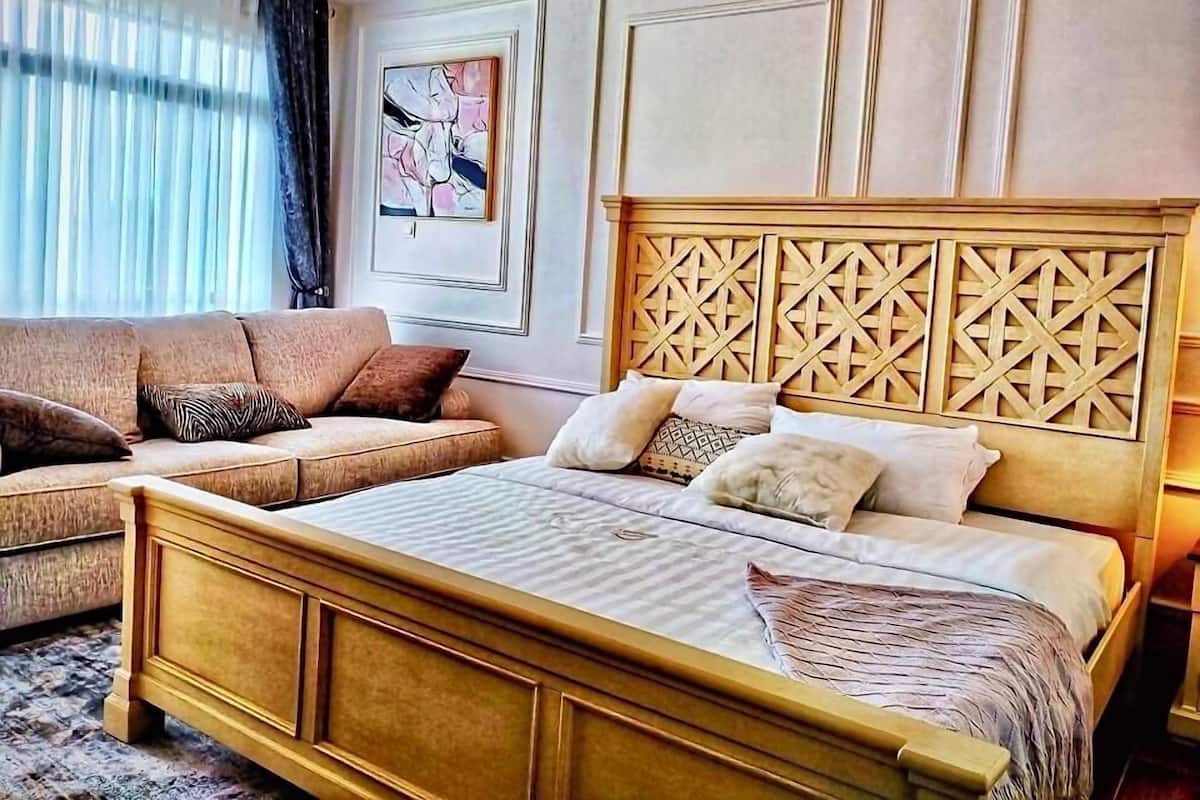 A bedroom with a bed, a sofa, and a decorative wall panel.