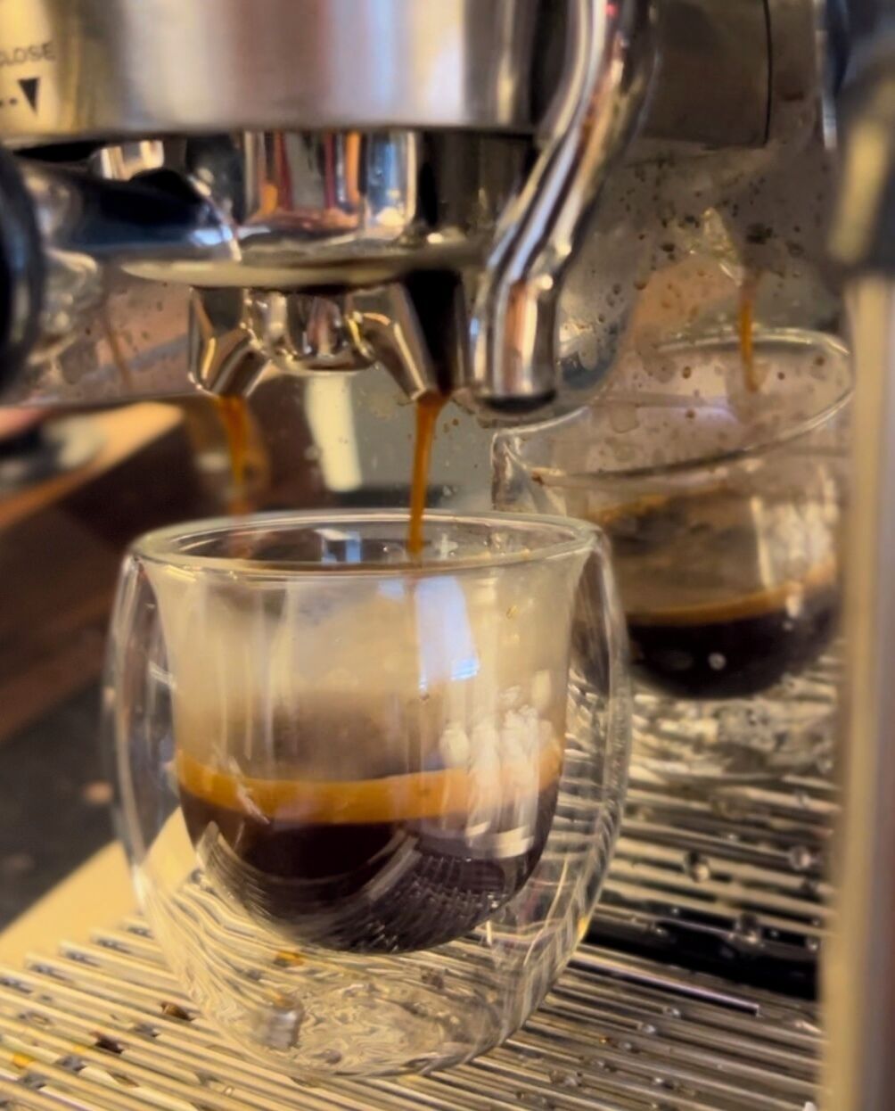 A coffee machine dispensing coffee into a glass cup.