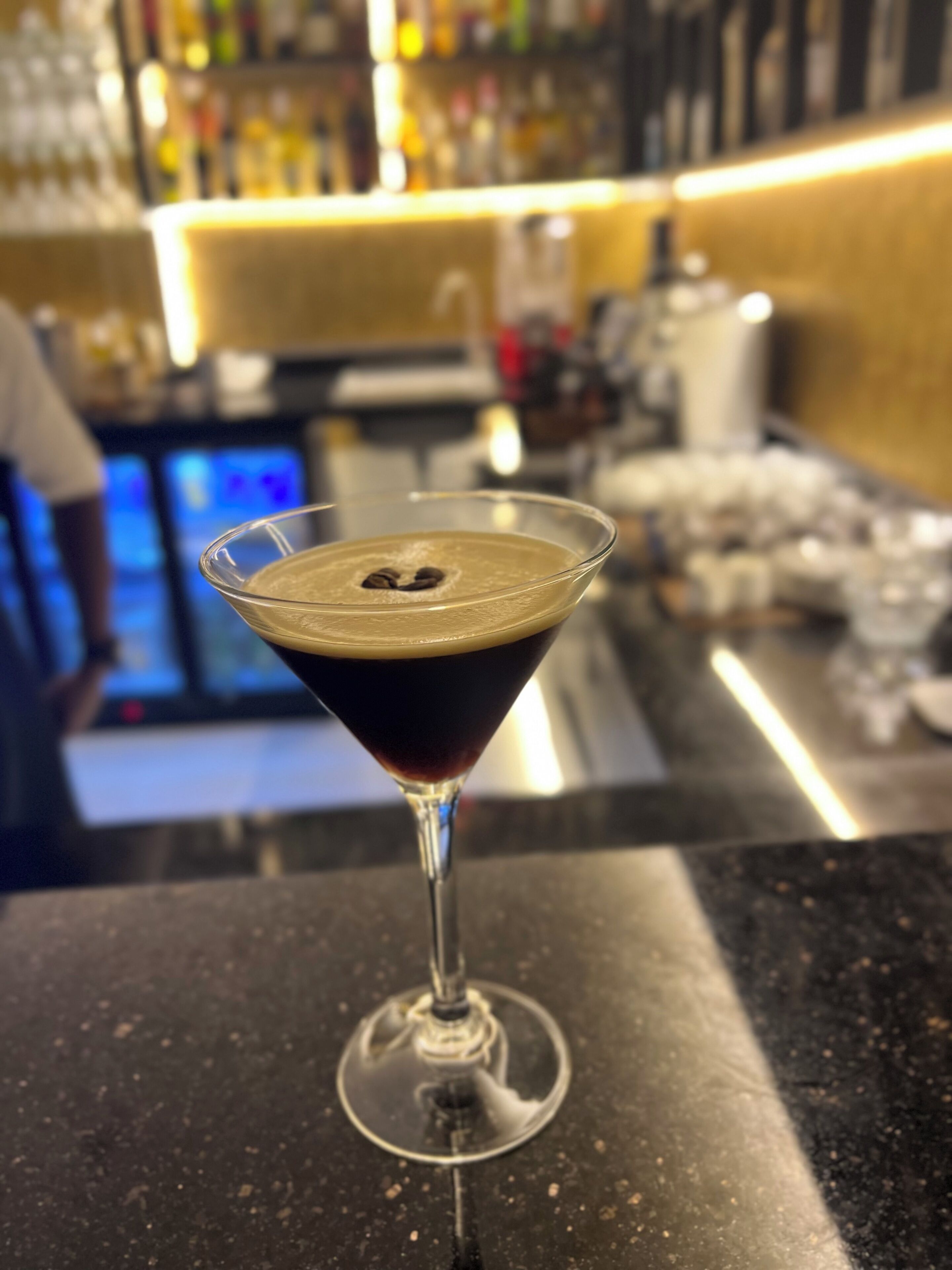 Un bicchiere da martini con un motivo a forma di cuore sul bordo, appoggiato a un bancone da bar.