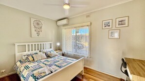 Un dormitori amb llit, escriptori i ventilador de sostre.