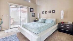 A bedroom with a bed, a nightstand, a dresser, a chair, a potted plant, and a sliding glass door leading to a balcony. - Super Central Scottsdale Location, 2-Bedroom 2-Bath 2 Balcony, Cozy Corner Condo (Scottsdale)