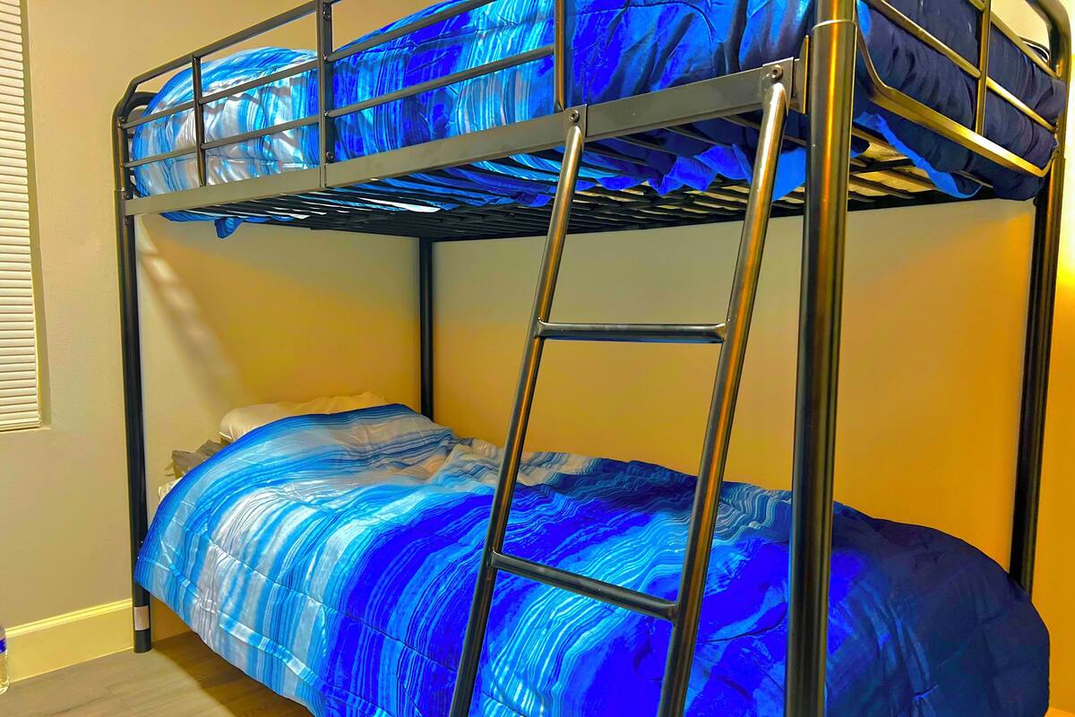 A bunk bed with a blue patterned bedspread and metal railings.