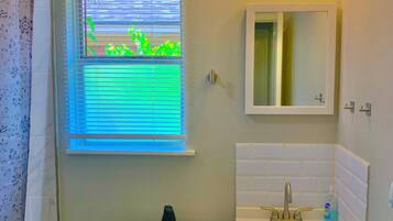 Baño con inodoro, lavabo y ventana con persianas.