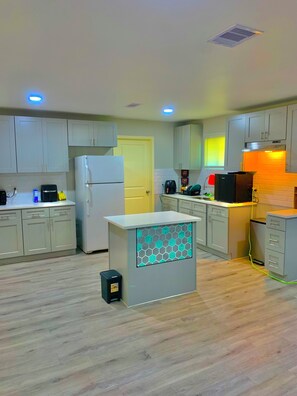 A modern kitchen with white cabinets, a central island, and a built-in oven.