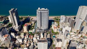 Un immeuble de grande hauteur à la conception circulaire, entouré d’autres bâtiments imposants, situé près d’une côte.