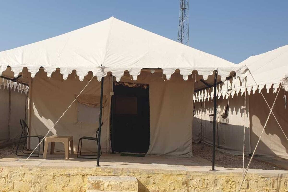 A row of white tents with a stone wall in the foreground.