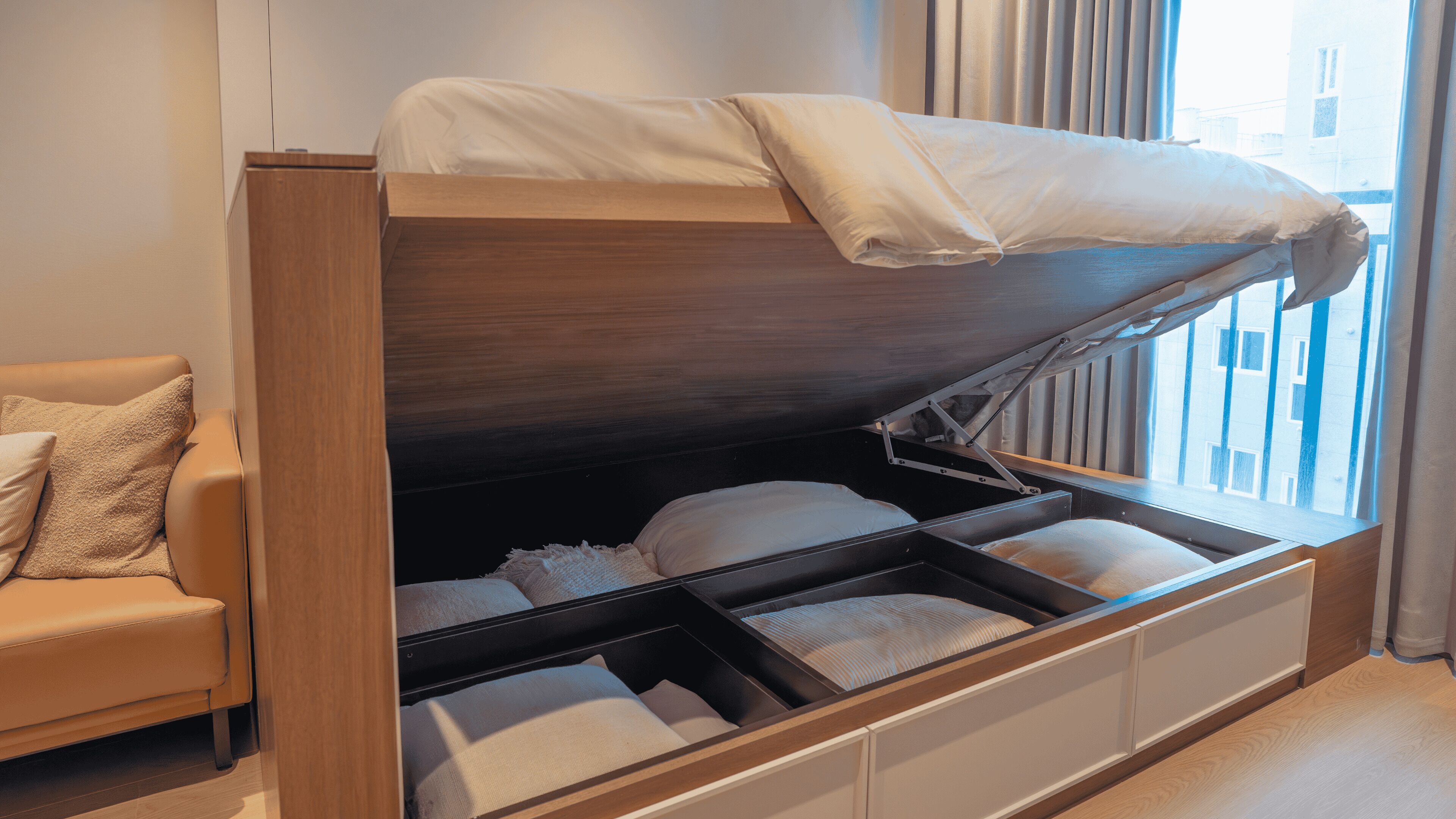 A bunk bed with a pull-out desk, a sofa, and a window with curtains.