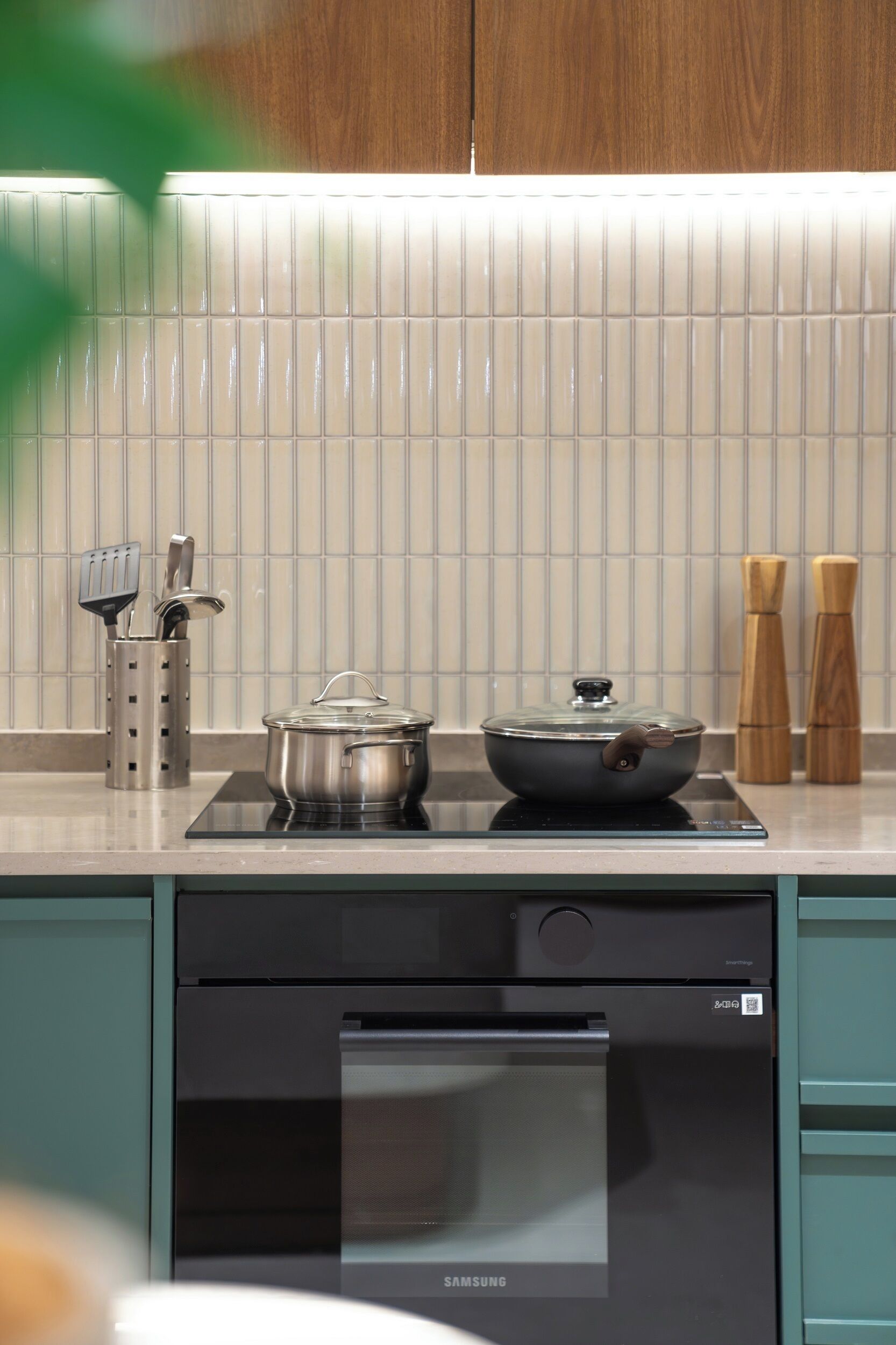 Una cocina moderna con estufa integrada, una olla sobre la placa de inducción y un horno Samsung en la parte inferior.