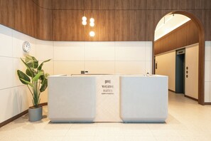 A reception desk with a clock, a potted plant, and a sign for 'weave suites SUNYU PARKSIDE.' - Weave Suites - Sunyu Parkside (Seoul)