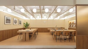 A modern conference room with wooden tables and chairs, a central island with a plant, and framed artwork on the walls. - Weave Suites - Sunyu Parkside (Seoul)