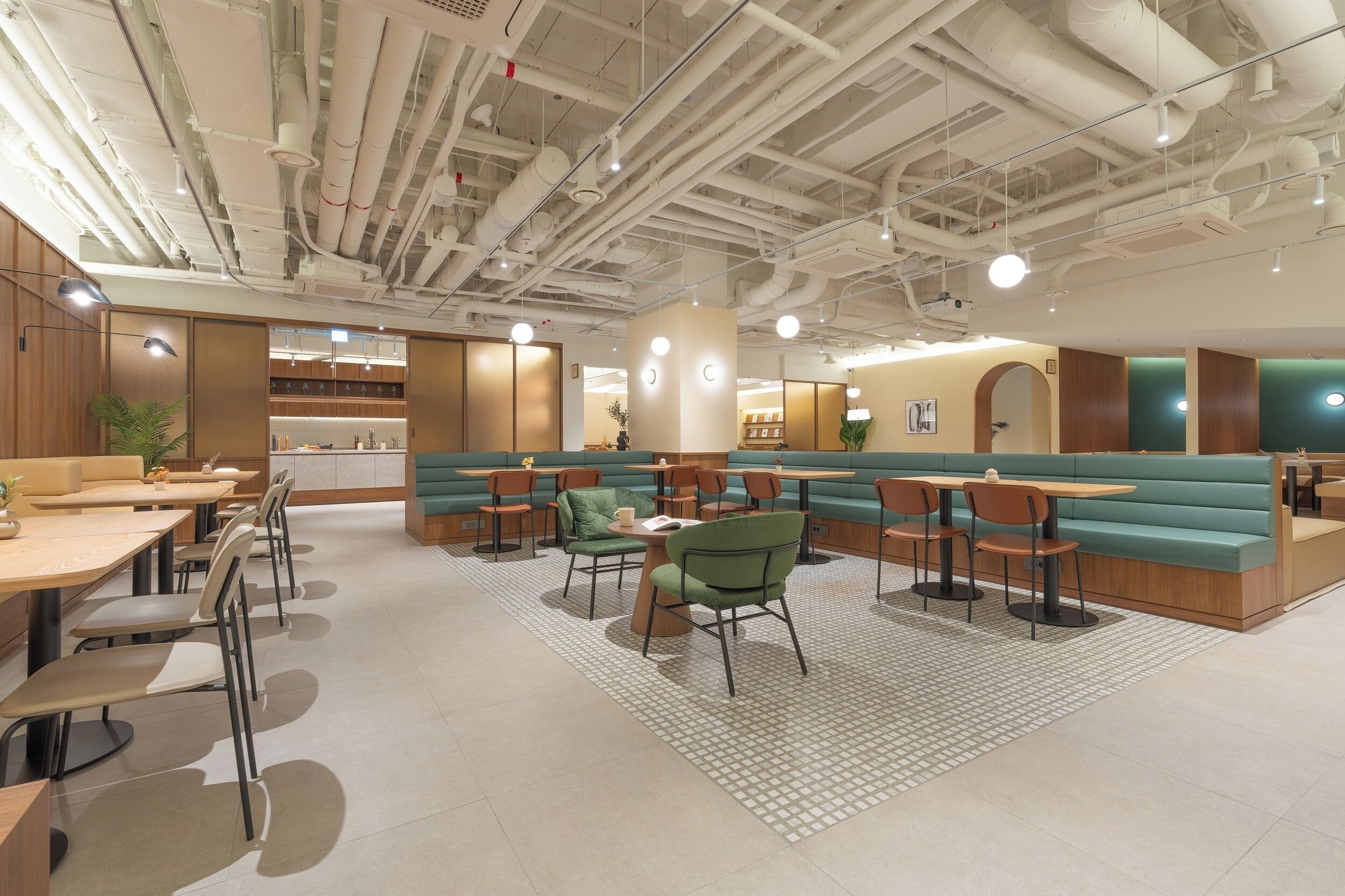 Un ristorante moderno con sedute a isola e tavoli, tubature a vista sul soffitto e un pavimento a motivi.