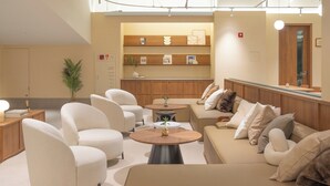 A modern lounge area with sofas, a coffee table, and a reception desk. - Weave Suites - Sunyu Parkside (Seoul)