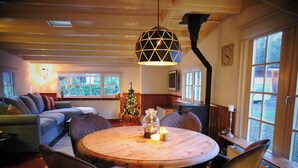 A cozy living room with a wooden dining table, comfortable seating, a Christmas tree, and large windows. - Cosy Cabin in the Woods - Perfect Get Away in a peaceful and green setting (Diessen)
