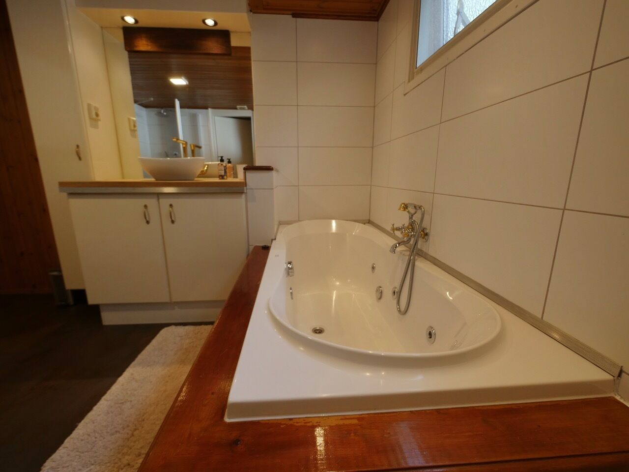 Une salle de bain moderne avec une baignoire sur pieds, un meuble-lavabo en bois et un grand miroir.
