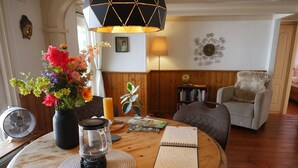 A cozy room with a round wooden table, a vase of flowers, a candle, and a notebook. - Cosy Cabin in the Woods - Perfect Get Away in a peaceful and green setting (Diessen)