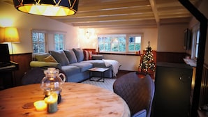 A cozy living room with a sofa, a small table with candles, a Christmas tree, and a fireplace. - Cosy Cabin in the Woods - Perfect Get Away in a peaceful and green setting (Diessen)